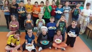 Uczniowie klasy 3d stoją w grupie, trzymając na talerzach przygotowane przez siebie zdrowe i kolorowe kanapki.