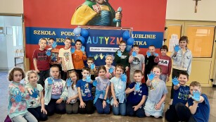 1.Dzień Świadomości Autyzmu. Klasa 2a z niebieskimi łapkami, obok napisu AUTYZM przed patronem szkoły.