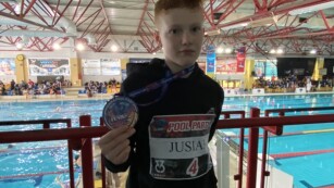 Brązowy medalista z medalem na tle basenu w Dębicy.
